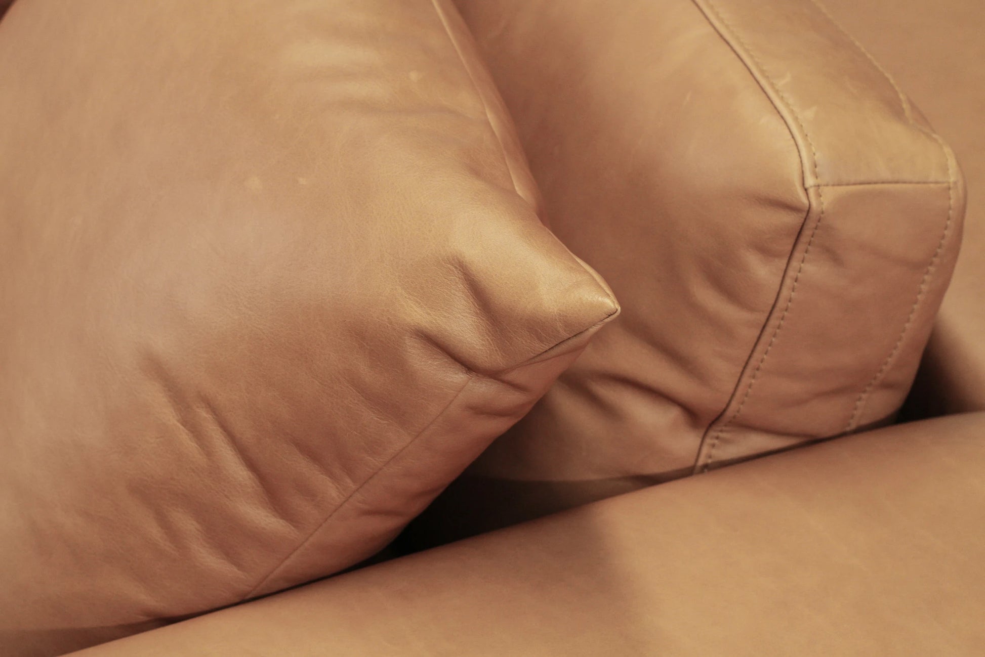 Close-up of a brown leather sofa with cushions