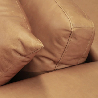 Close-up of a brown leather sofa with cushions