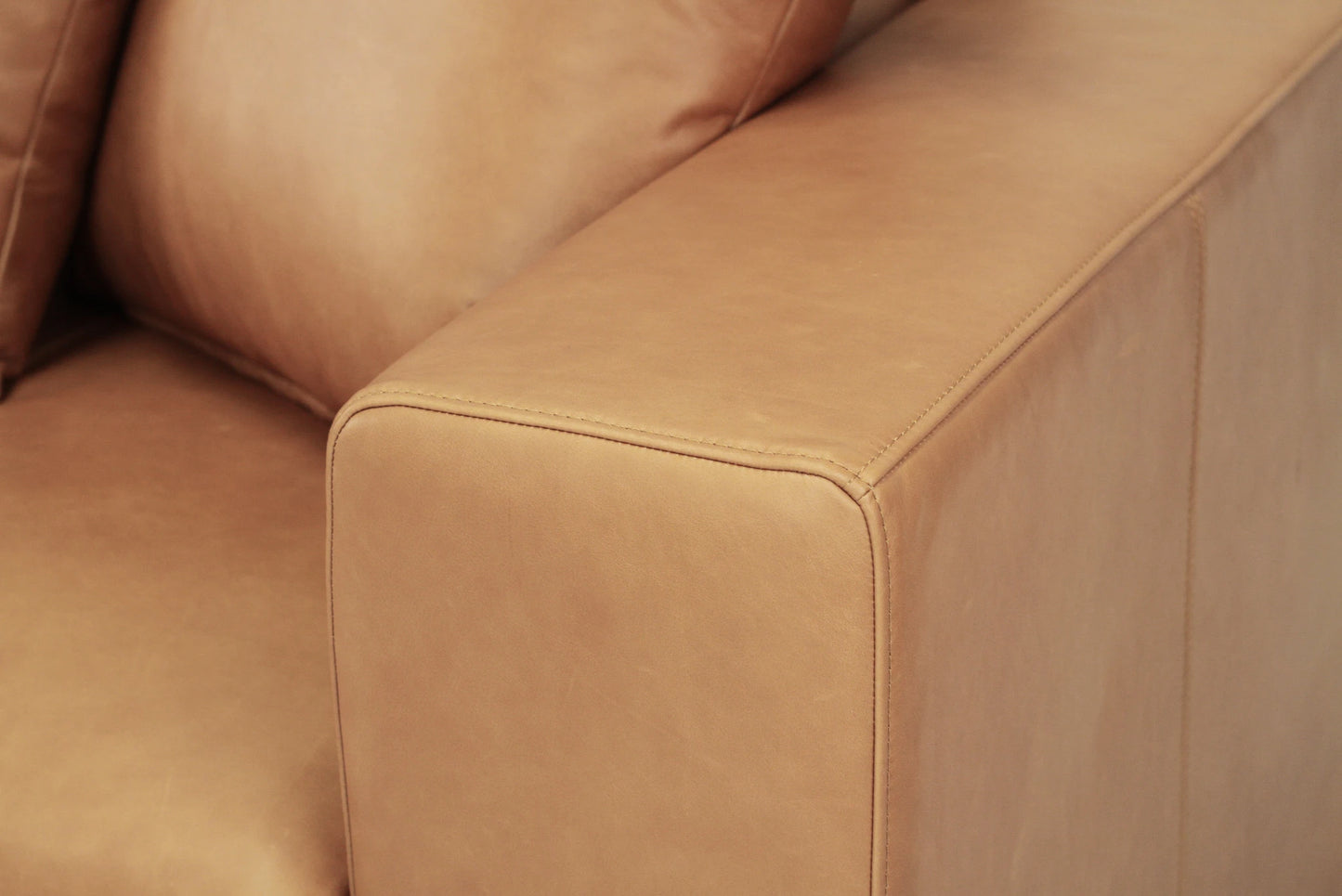 Close-up of a tan brown leather sofa corner