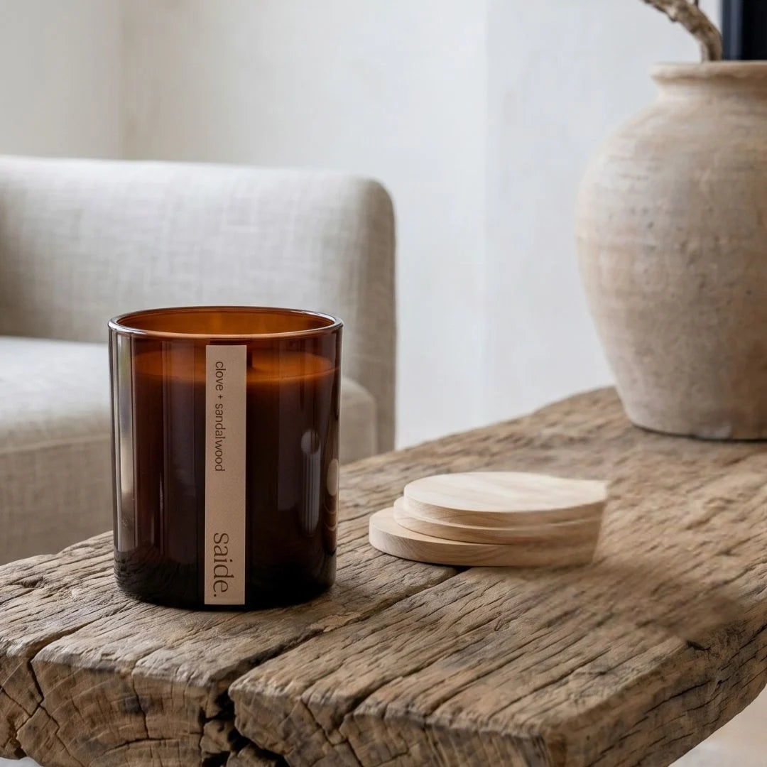 Brown candle with a label on a wooden surface, with a neutral background