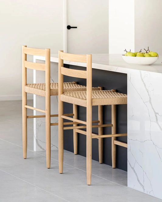 Two wooden bar stools with woven seats in a modern kitchen.
