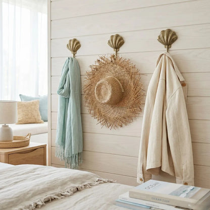 Decorative shell hooks on a wall with a hat, scarf, and books in a bedroom setting.