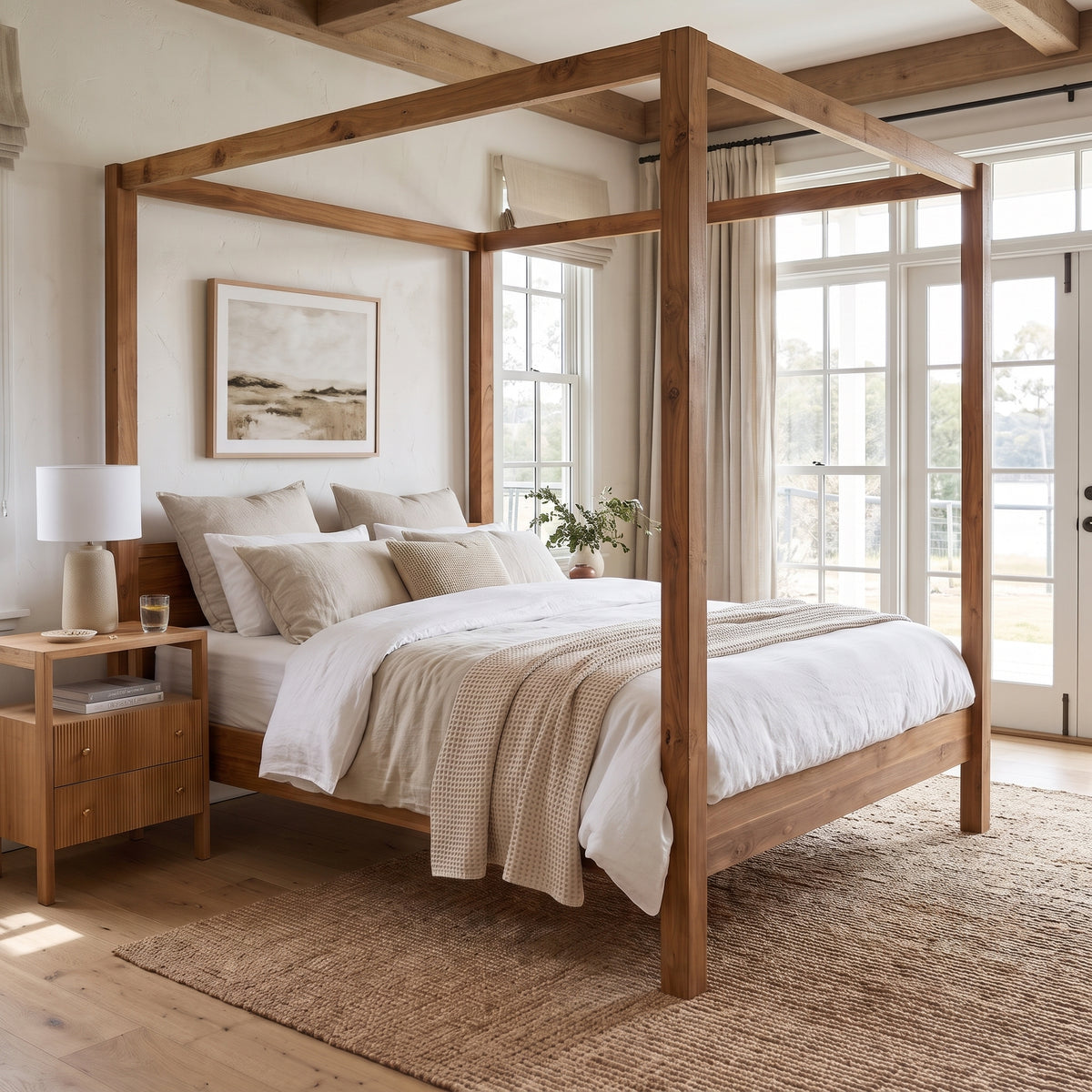 A rustic four-poster canopy bed made of natural medium-brown wood, dressed in white and beige bedding, set in a bright, modern bedroom with a matching wood nightstand and a woven jute rug.