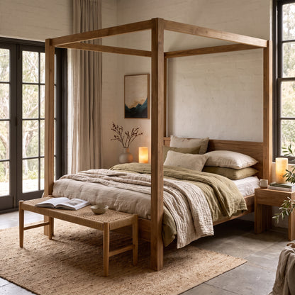 A rustic four-poster canopy bed in natural wood, styled with neutral beige and olive green bedding, set in a bright, modern bedroom with large windows and a matching wooden bench at the foot of the bed.