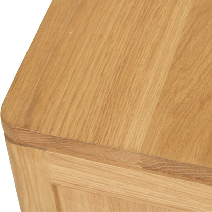 Close-up of a light oak wood cabinet corner showing the top surface, rounded edge, and front panel with visible wood grain.