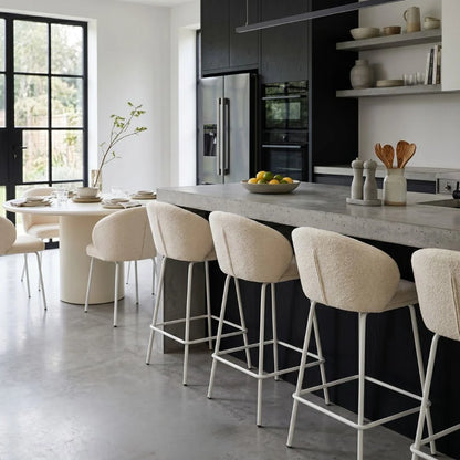 Modern kitchen with bar stools and a dining table.