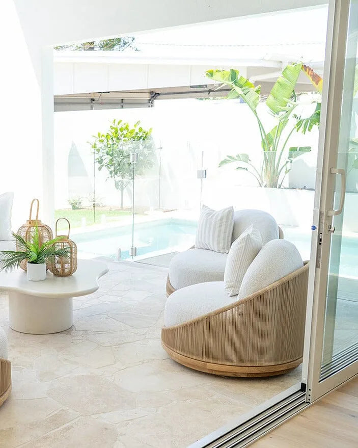 Modern outdoor living space with white furniture, a pool, and plants.