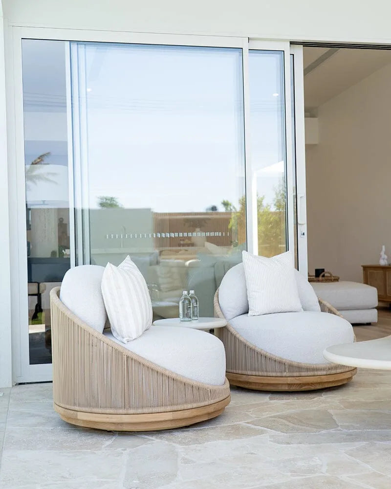 Modern outdoor furniture set with white cushions on a patio.
