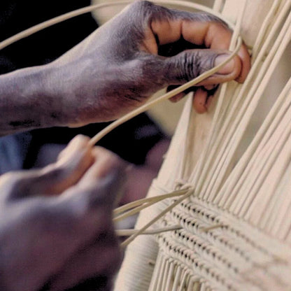 Close-up of hands weaving with natural fibers.