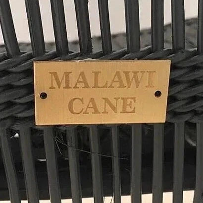 Black cane chair with a gold 'Malawi Cane' label on a white background
