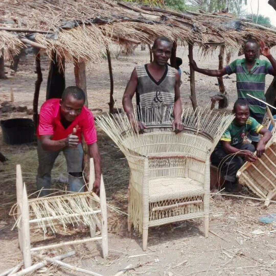 People working on woven furniture in a rustic outdoor setting