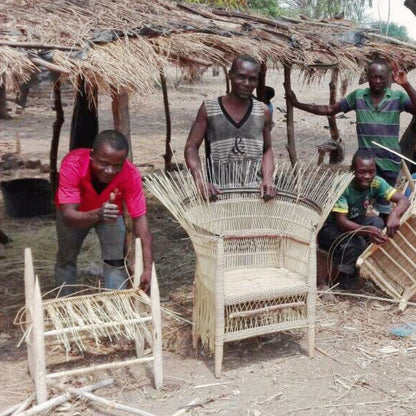 People working on woven furniture in a rustic outdoor setting