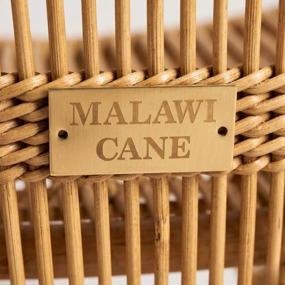 Wicker basket with 'Malawi Cane' label on a blurred background