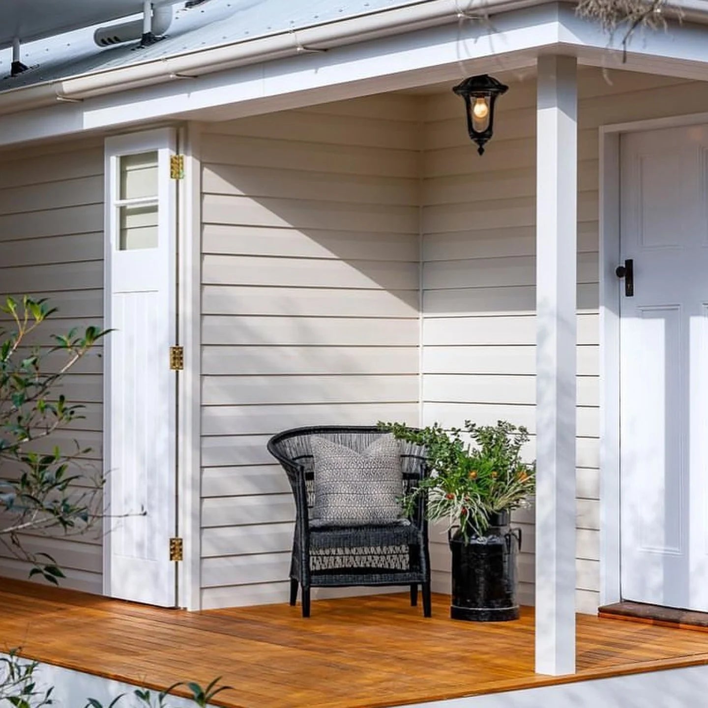 Front porch with a black Malawi Cane chair, potted plants, and a light fixture.