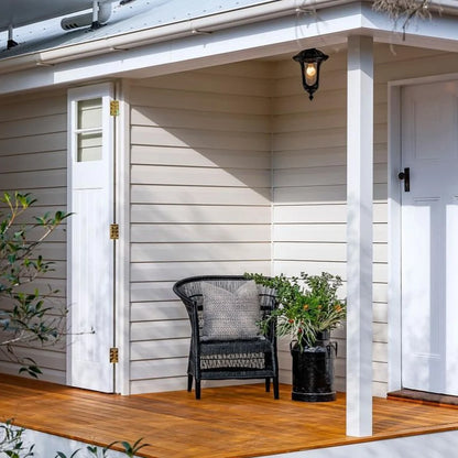 Front porch with a black Malawi Cane chair, potted plants, and a light fixture.