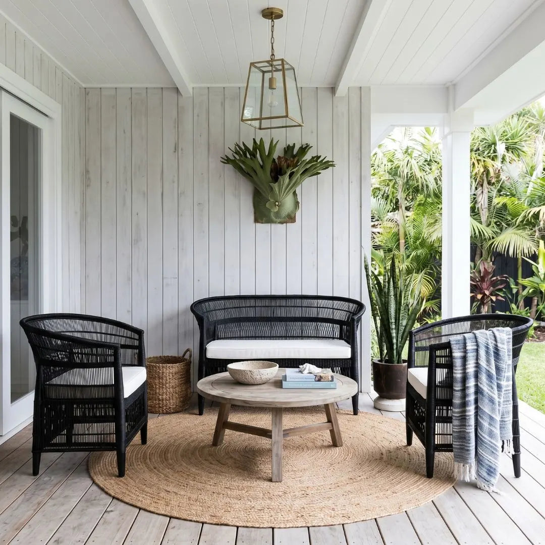 Outdoor patio with black wicker furniture, wooden table, and plants.