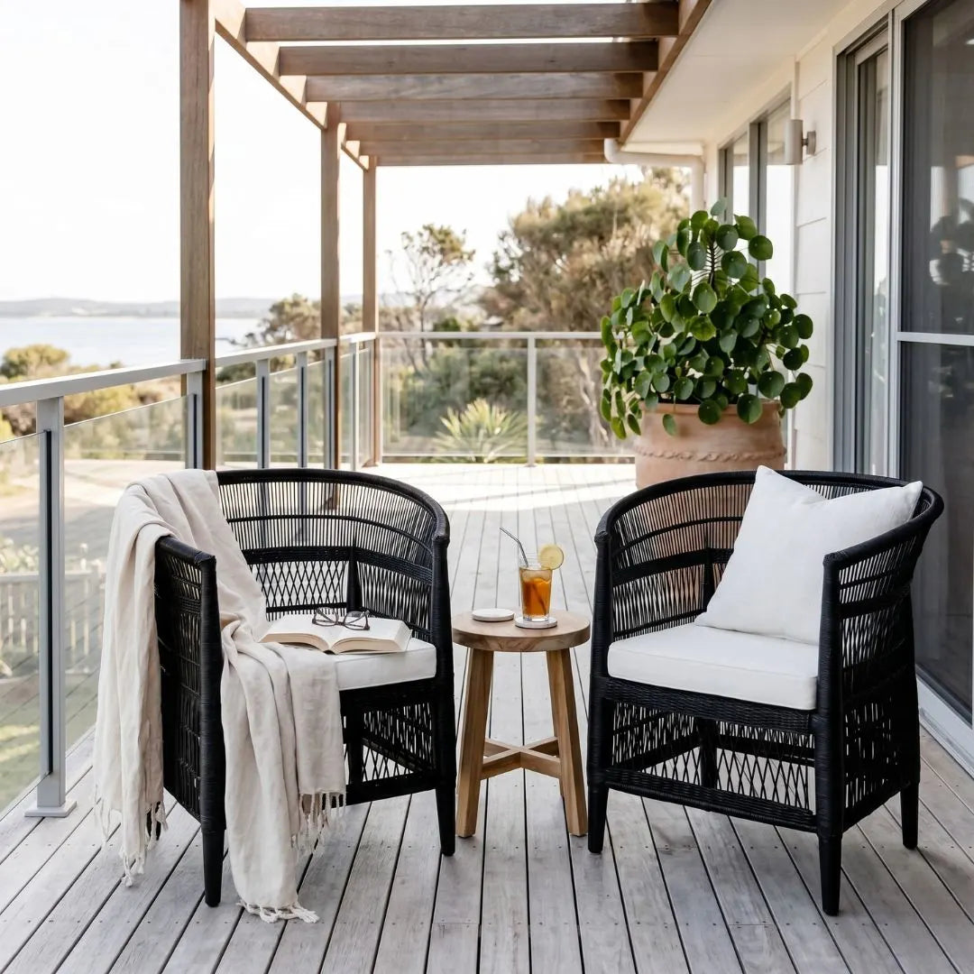 Outdoor seating area with black wicker chairs, a small table, and a view of the ocean.
