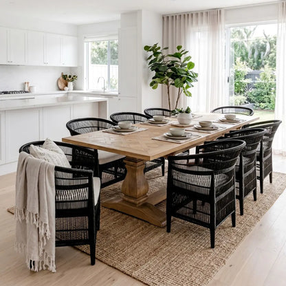 Dining room with a wooden table and black chairs on a wooden floor.