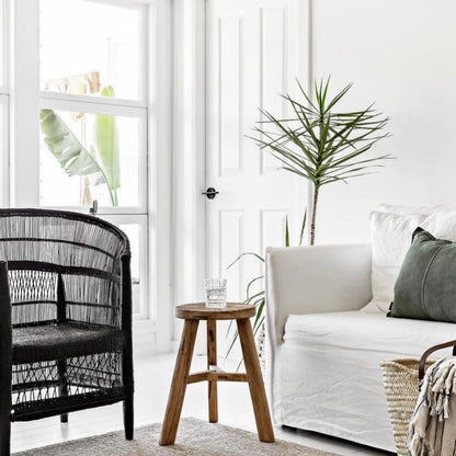 Modern living room with black wicker chair, wooden stool, and white sofa.