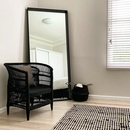 Black Malawi Cane chair and mirror in a room with a bed and window.