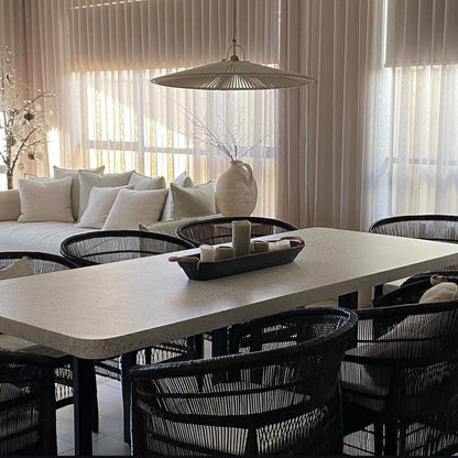 Modern dining room with a long table and black Malawi Cane chairs, featuring a vase and decorative items.