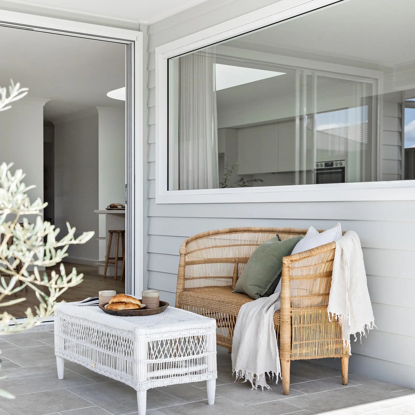 Outdoor seating area with wicker furniture and a white table on a patio.