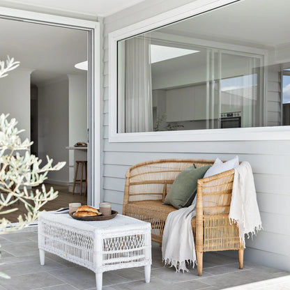 Outdoor seating area with wicker furniture and a white table on a patio.