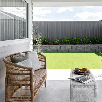 Outdoor patio with wicker bench, coffee table, and view of garden