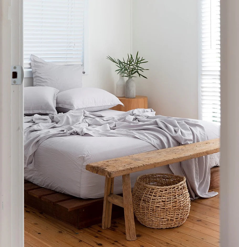 Bedroom with a wooden bench and wicker basket at the foot of the bed.
