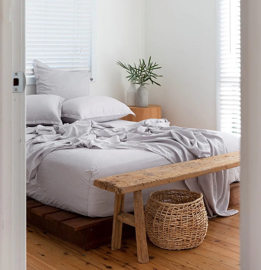 Bedroom with a wooden bench and wicker basket at the foot of the bed.