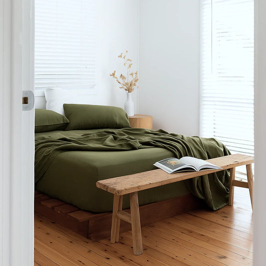 Bedroom with green bedding and wooden bench