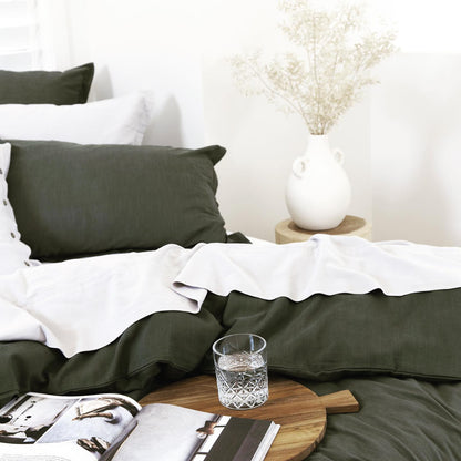 Green and white bedding with a glass of water on a wooden table.