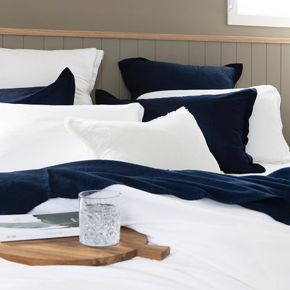 Bed with navy and white pillows and a glass of water on a wooden tray.