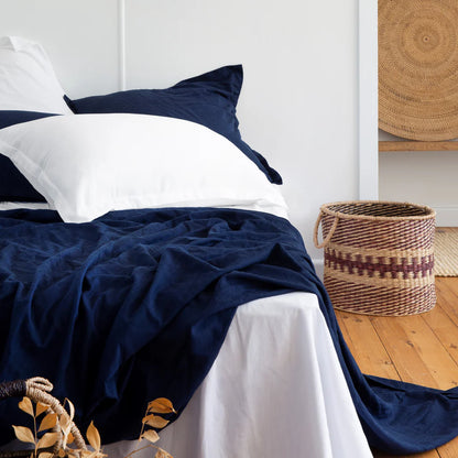 Navy blue and white bedding on a bed with a woven basket in the background.