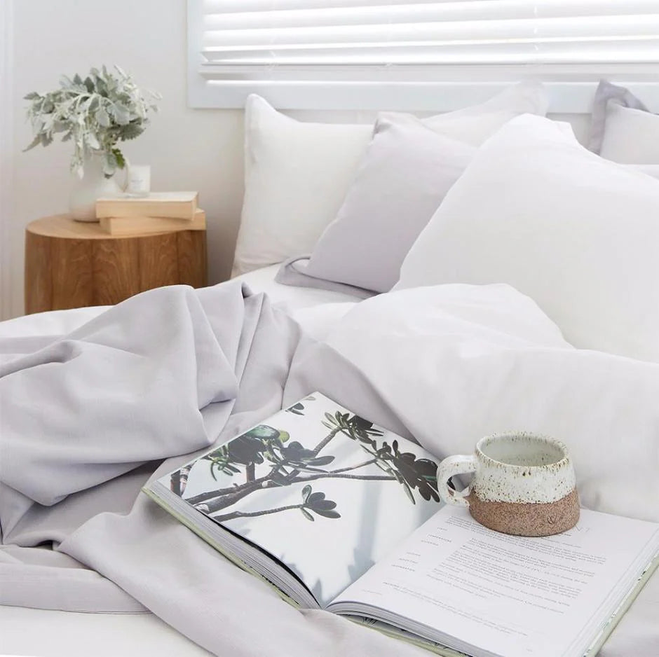 Bedroom with an open book and mug on a white bedspread