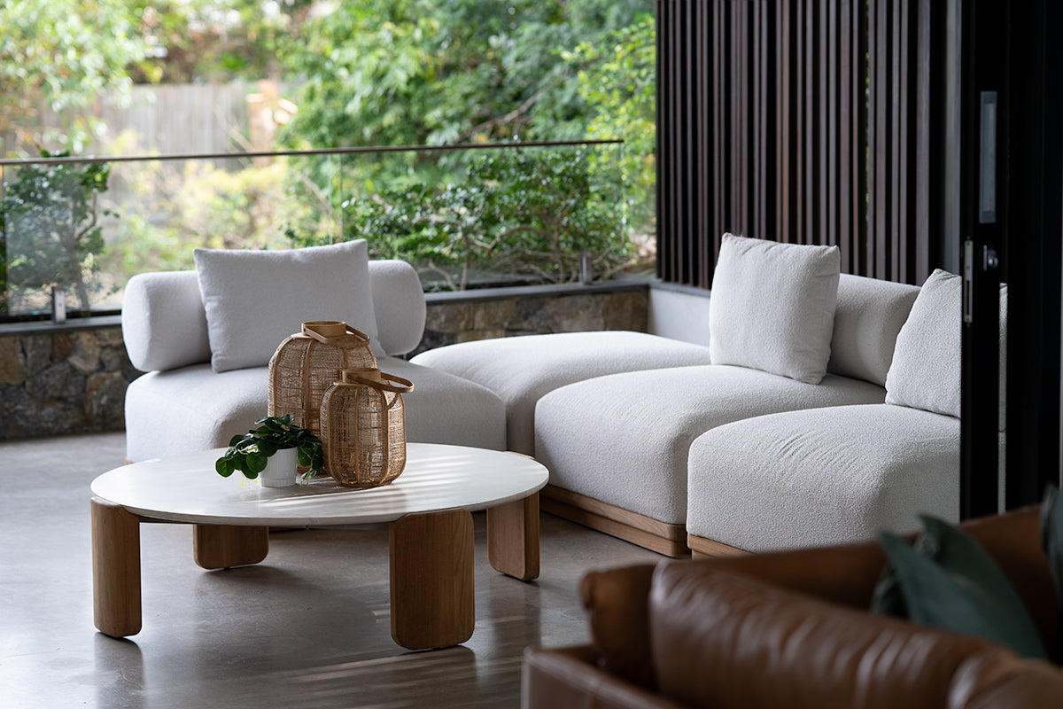 Modern outdoor living space featuring Sun Republic Baska outdoor white sectional sofa, wooden coffee table, and decorative items.