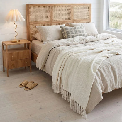 Neatly made bed with beige bedding in a bedroom setting.
