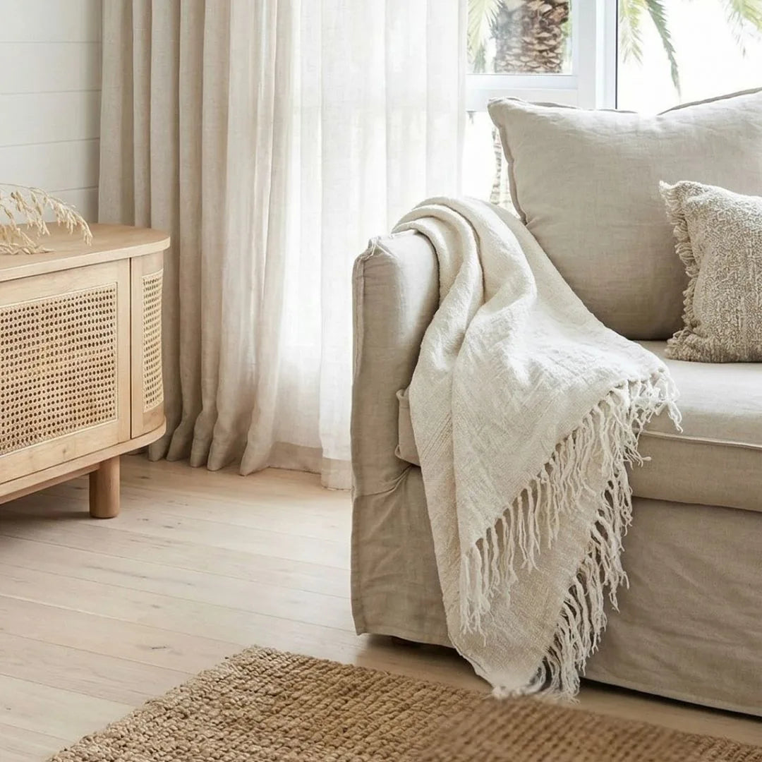 Cozy living room with beige sofa, white throw blanket, and wooden cabinet.