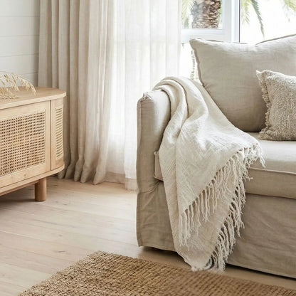 Cozy living room with beige sofa, white throw blanket, and wooden cabinet.