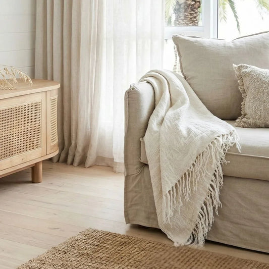 Cozy living room with beige sofa, white throw blanket, and wooden cabinet.