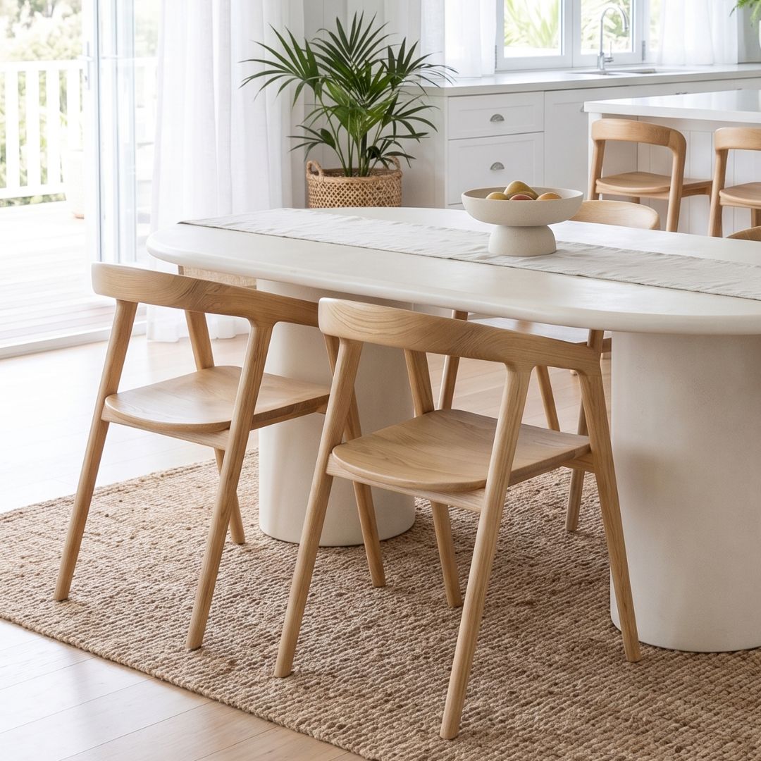 Dining area with a white table and wooden chairs in a bright room.