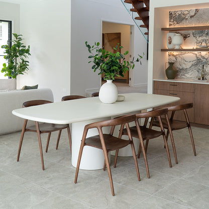 Modern dining area with a white table and wooden chairs in a bright room.
