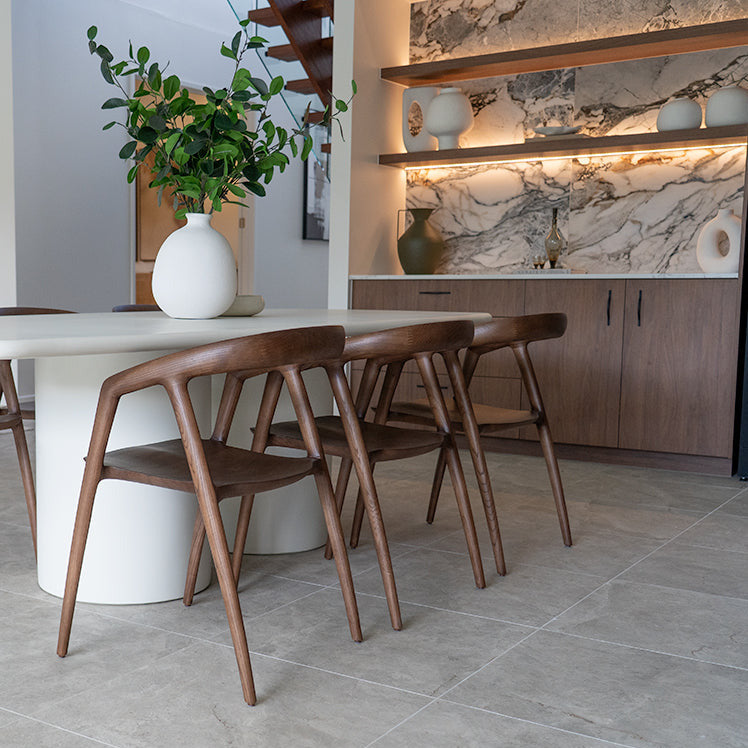 Modern dining area with a white round table and wooden chairs in a stylish interior.