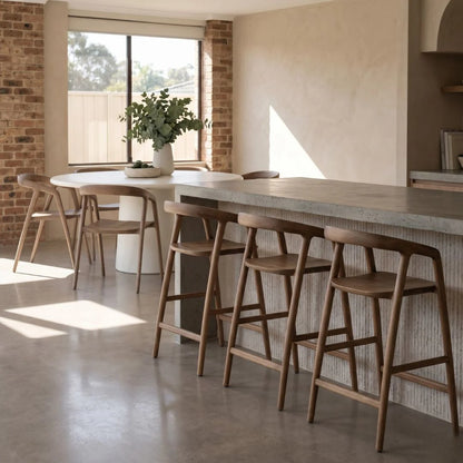 Modern kitchen with wooden bar stools and a concrete countertop.
