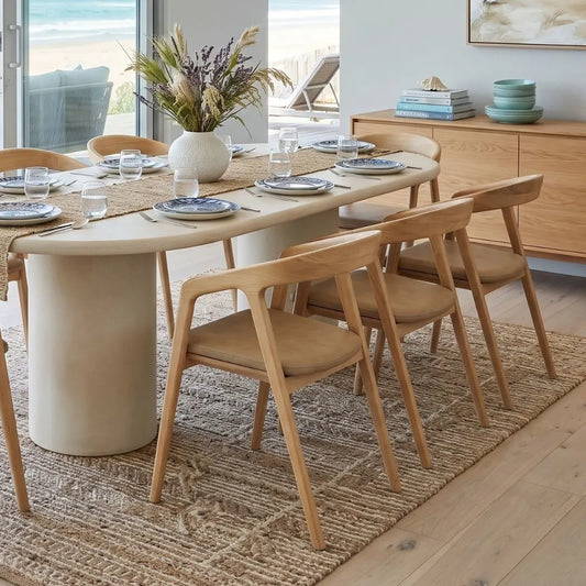 Dining room with a beige table and wooden chairs on a textured rug.