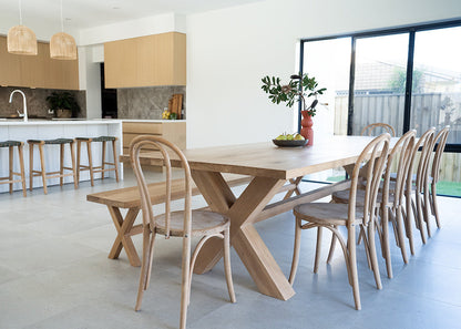 Modern kitchen and dining area with wooden furniture and large windows.