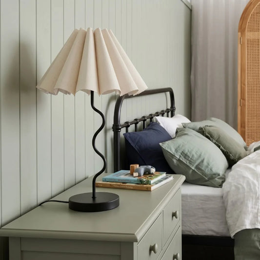 Lamp on a nightstand next to a bed with pillows