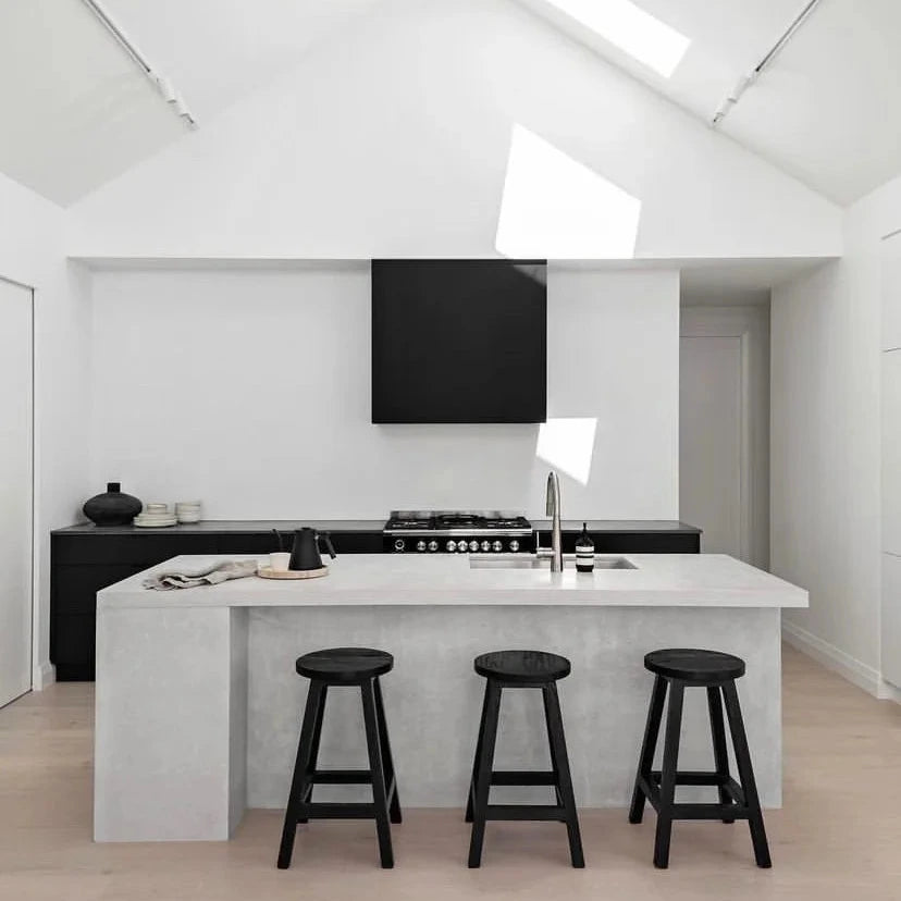 Modern kitchen with white island, black bar stools, and white walls.