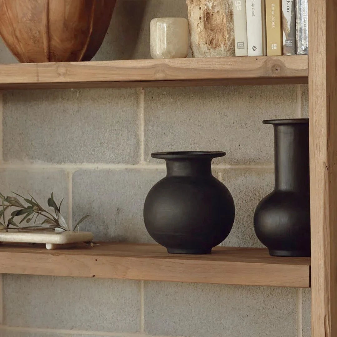 Two black ceramic vessels on a wooden surface with a white background by Sun Republic