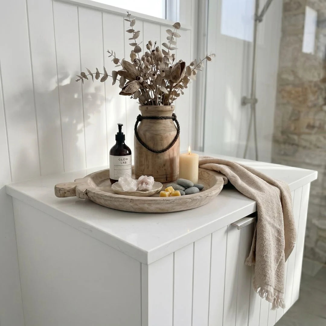 Bathroom counter with decorative items including a vase with dried plants, bottles, and a candle.